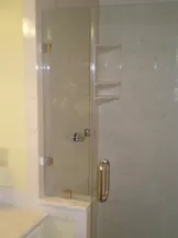 Bathroom Remodeling New Walk-In Shower with Beige Tiles. Bronze Colored Ceiling Mounted Showerhead. and Hardware. Glass Door with Brass Handle